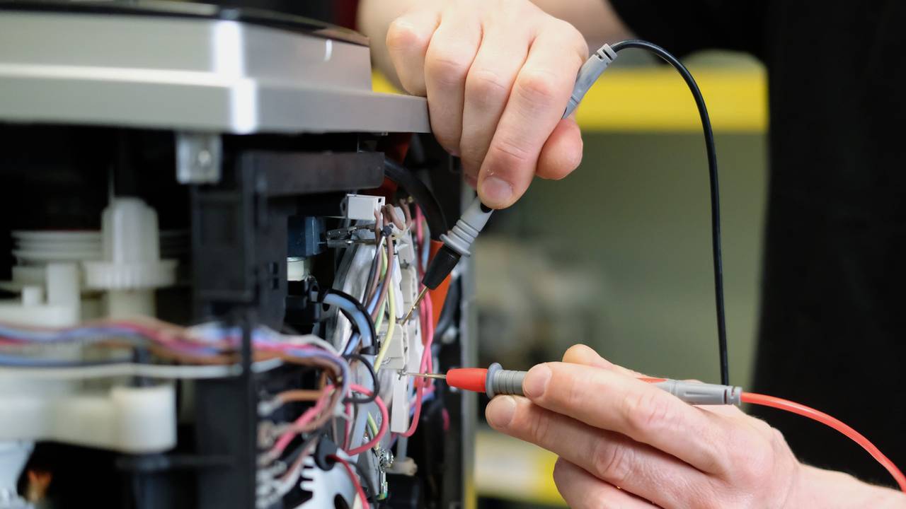 An einem Kaffee-Vollautomaten in einer Reparaturwerkstatt werden elektronische Messgrößen ermittelt.