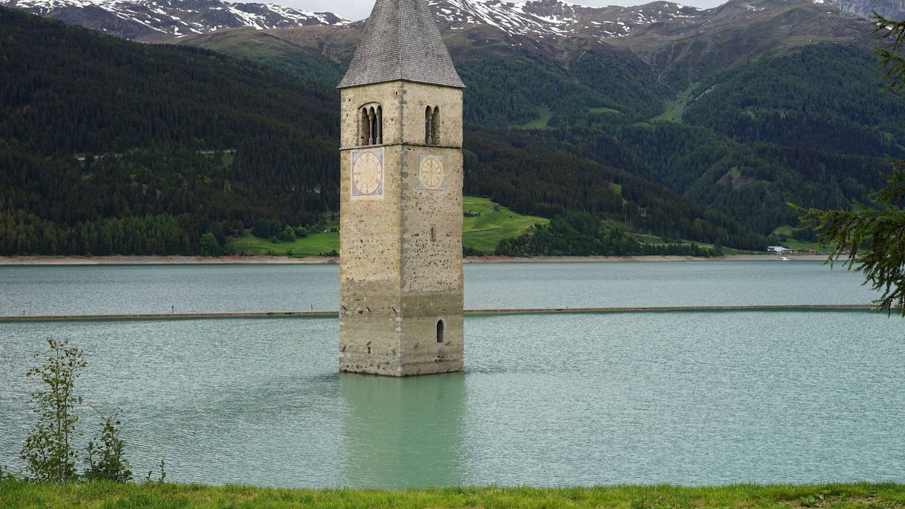 Der Kirchturm des alten Dorfes ragt aus dem Reschensee in Südtirol.