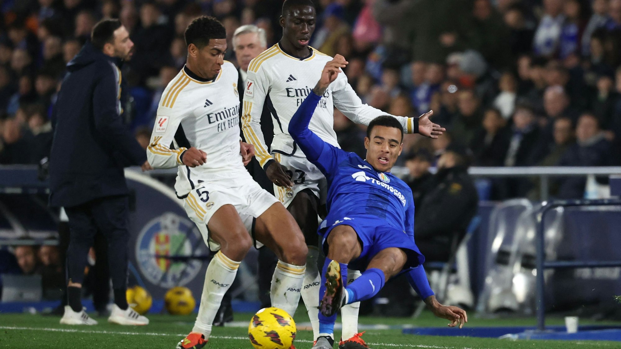 Jude Bellingham (l.) bearbeitet gemeinsam mit Real-Teamkollege Ferland Mendy seinen Gegenspieler Mason Greenwood vom FC Getafe.