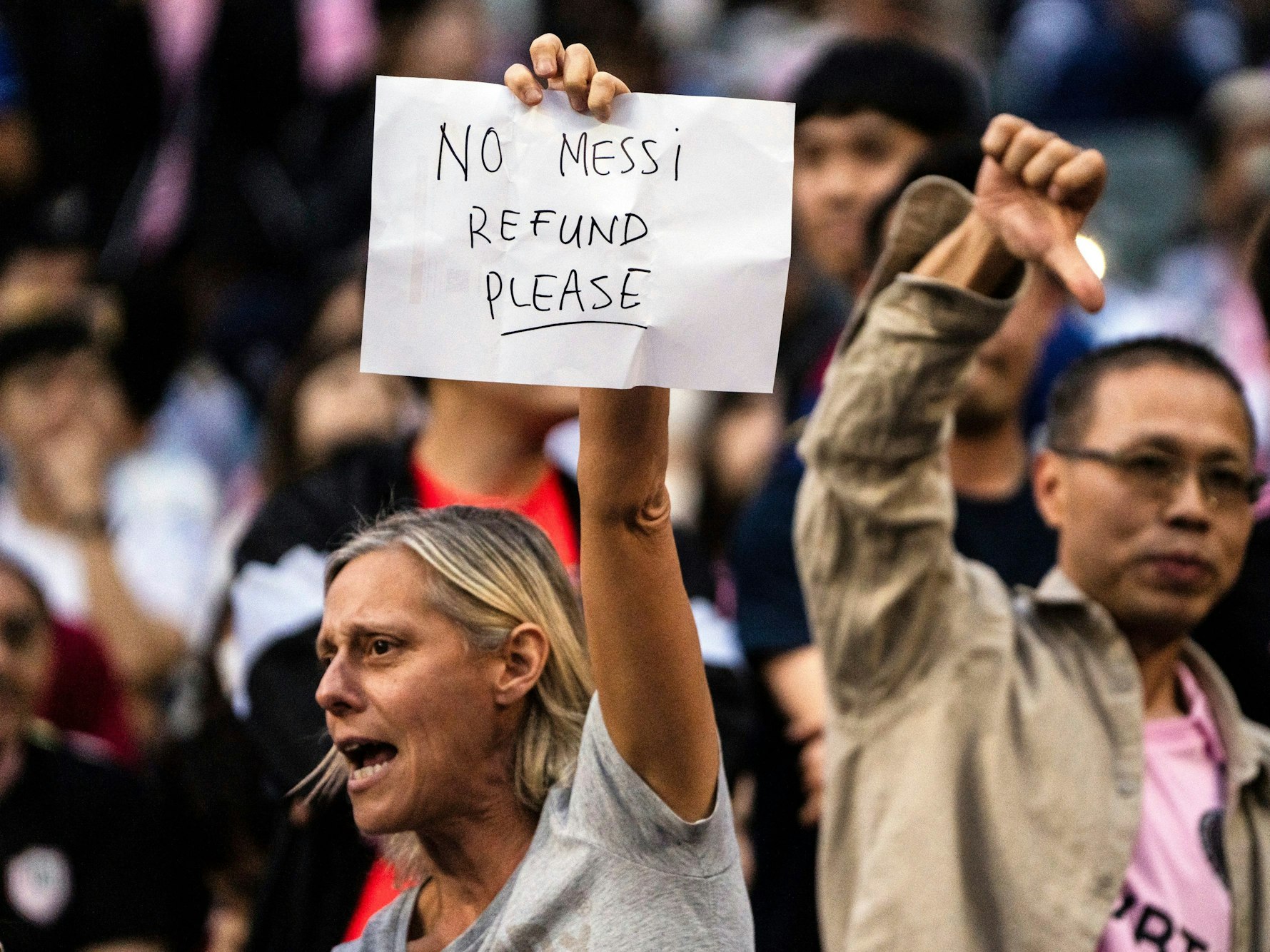 Dieser weibliche Fan beschwerte sich mit einem Zettel für die Abwesenheit von Messi, der Mann hinter hier zeigt den Daumen runter. (Foto: 4. Februar 2024)