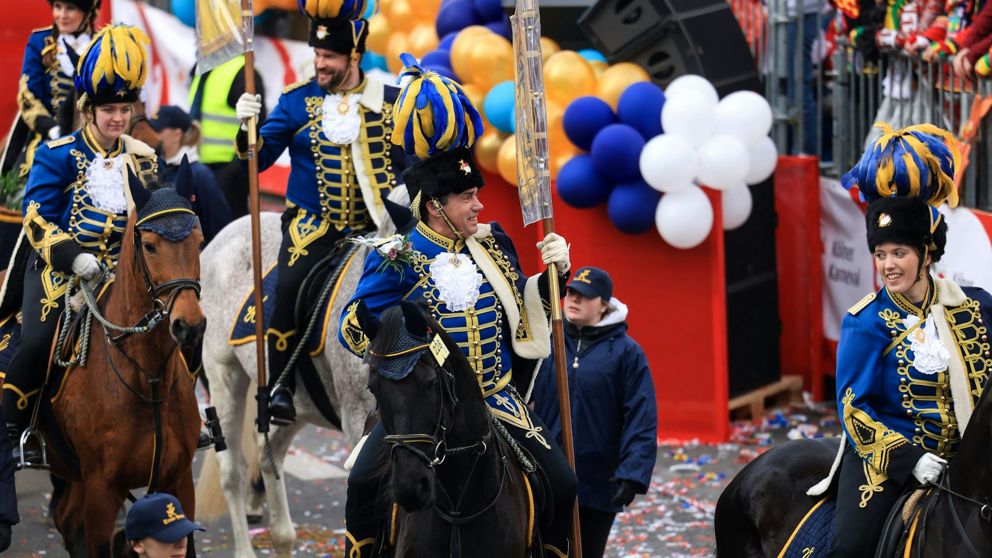 Reiter auf Pferden laufen im Festumzug mit.