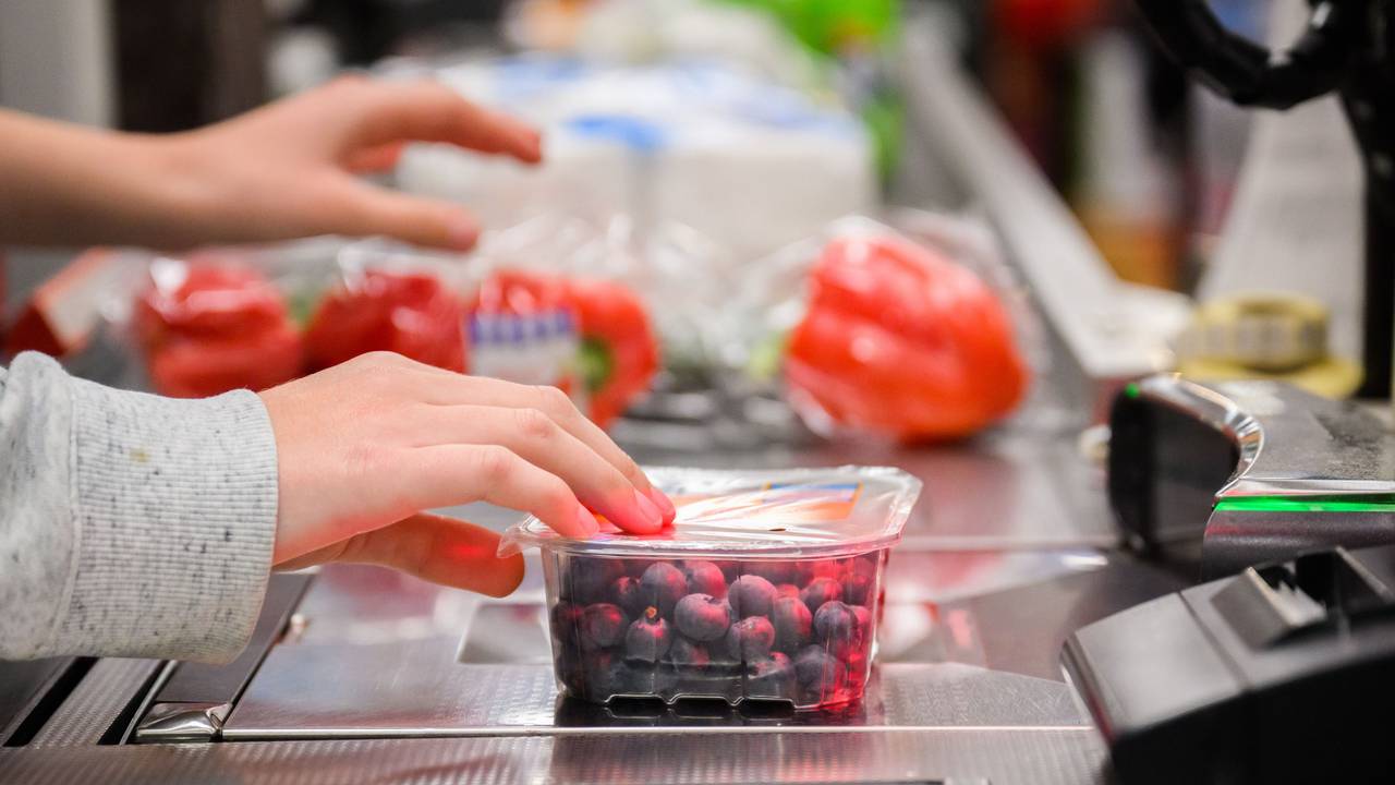 Eine Kassiererin scannt Heidelbeeren an der Kasse eines Supermarktes.