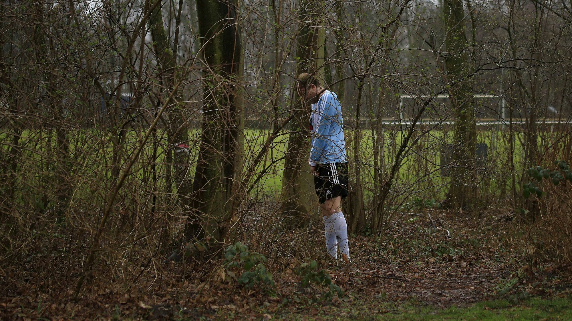 Ein Spieler des FC Büderich musste auf dem Weg von der Kabine zum Spielfeld einem dringendem Bedürfnis nachgeben und suchte sich dafür das Gestrüpp am Wegesrand aus.