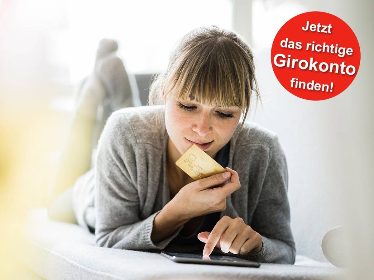 Eine Frau liegt auf dem Sofa und hält eine Bankkarte in der Hand während sie auf ihrem Tablet etwas eingibt.