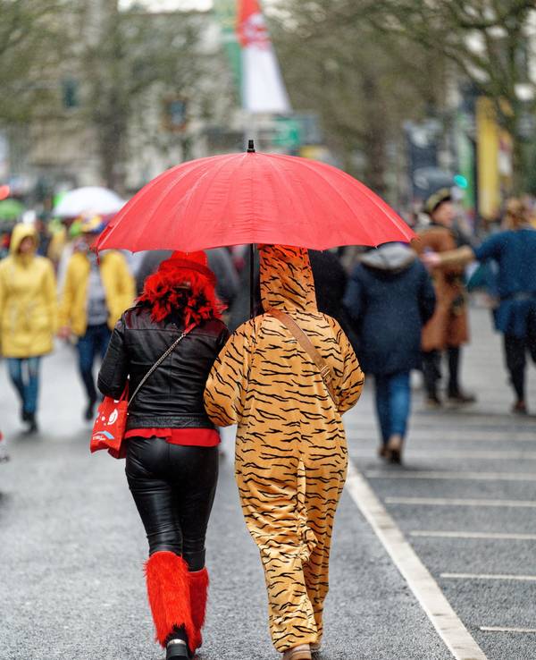 Verkleidete Karnevalisten unterwegs mit Regenschirm.