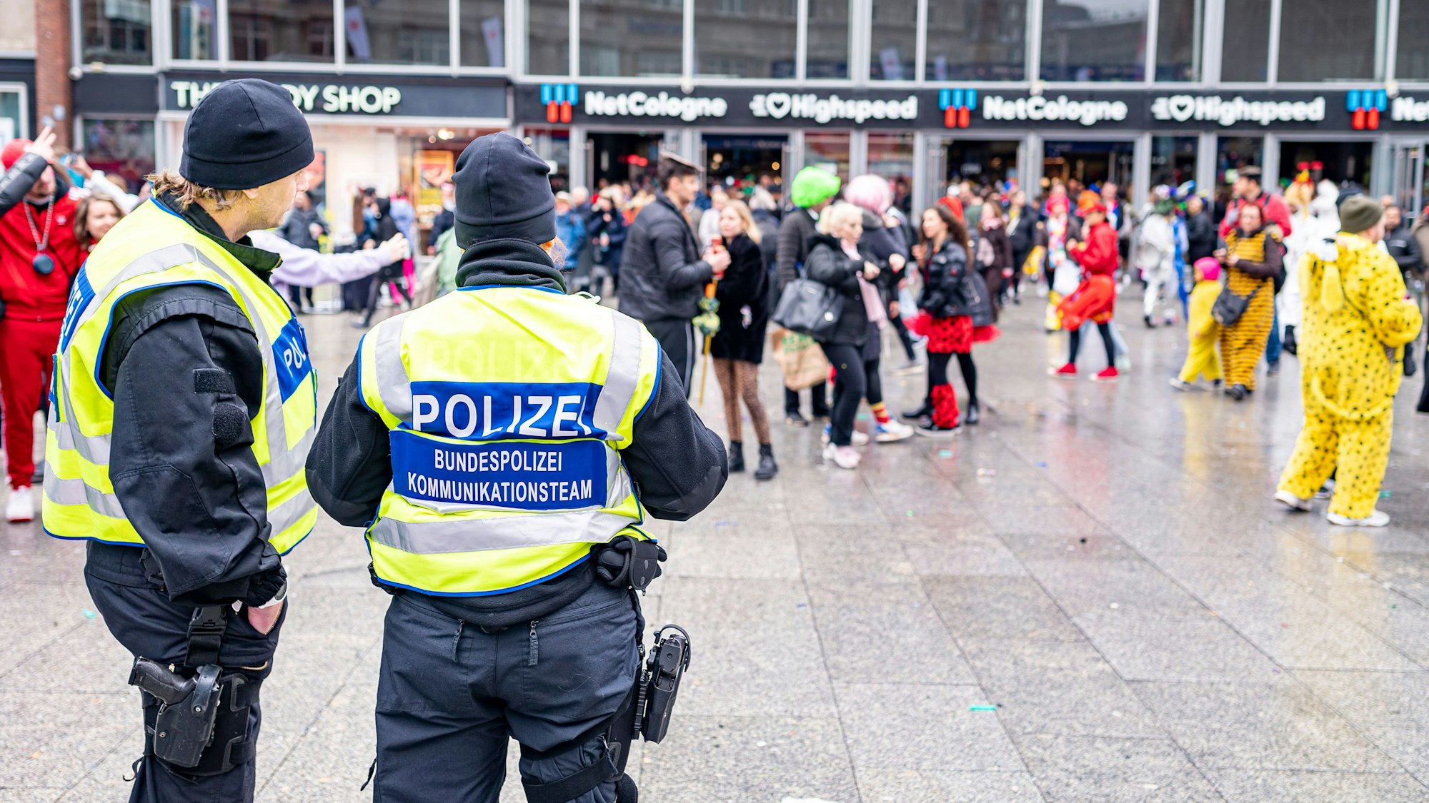 Zwei Bundespolizisten stehen vor einer Menge verkleideter Menschen.