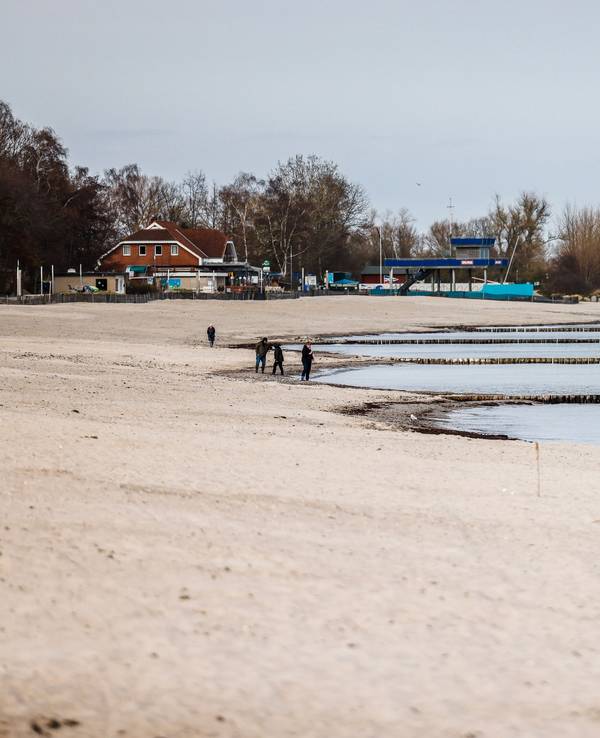 Personen am Starnd im Ostseebad Kellenhusen spazieren, hier im März 2022.