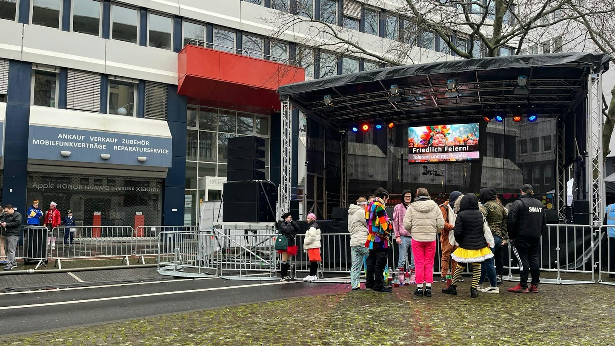 Ein paar verkleidete Menschen stehen vor einer großen Bühne.