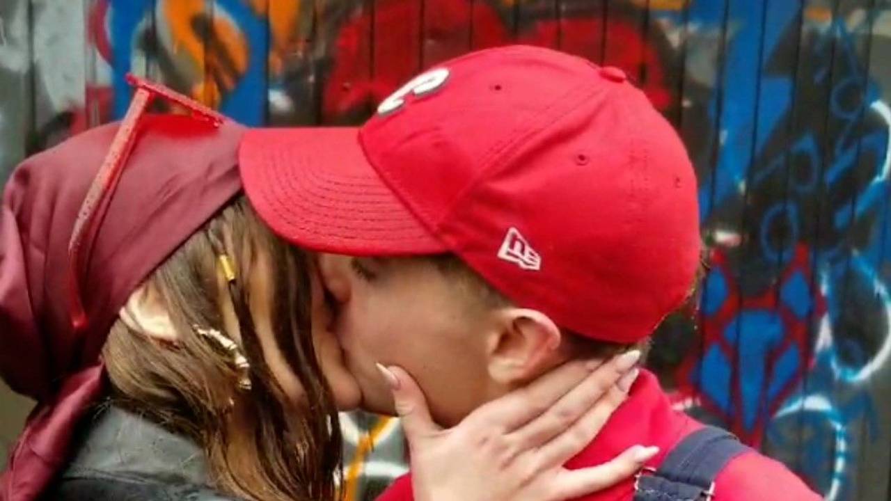 Eine junge Frau und ein junger Mann geben sich einen Kuss.
