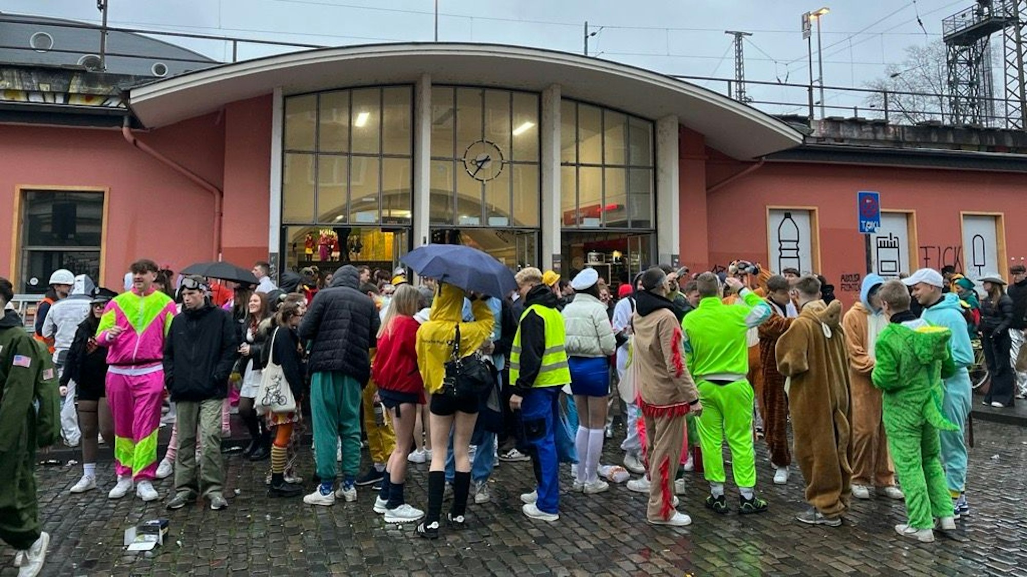 Kostümierte stehen vor einem Bahnhofsgebäude in Köln.