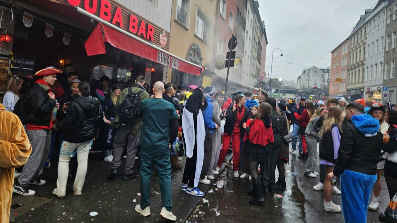 Menschen feiern vor einer Bar auf der Zülpicher Straße.