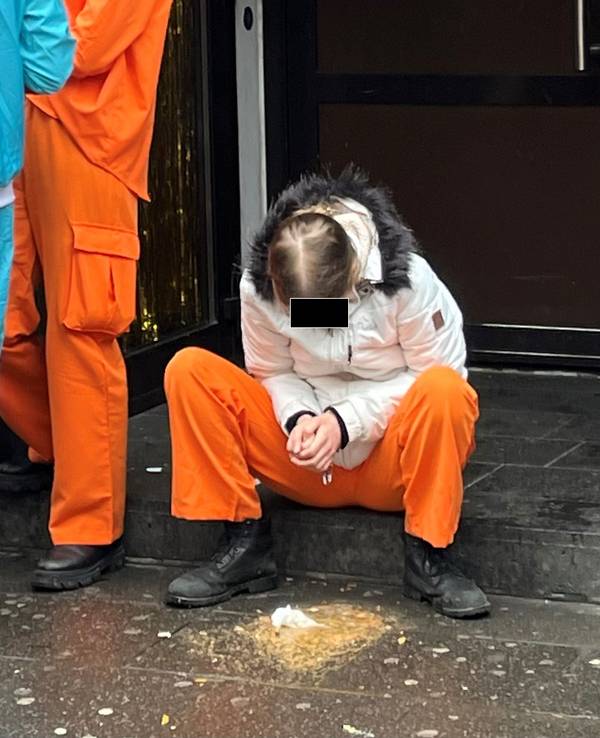Eine junge Person sitzt auf der Stufe eines Hauseingangs und hat sich erbrochen.