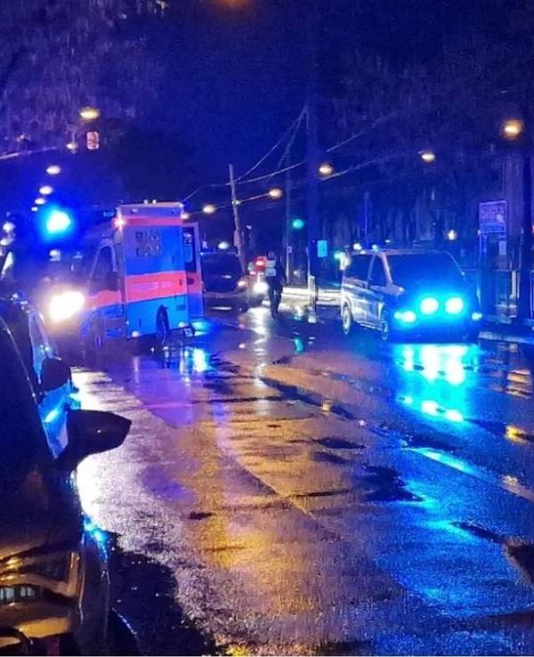 Ein Rettungswagen und ein Polizeifahrzeug stehen auf einer regennassen Straße.