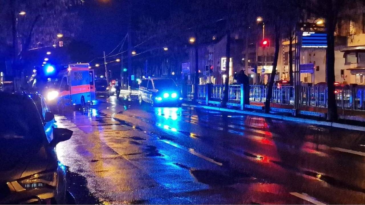 Ein Rettungswagen und ein Polizeifahrzeug stehen auf einer regennassen Straße.