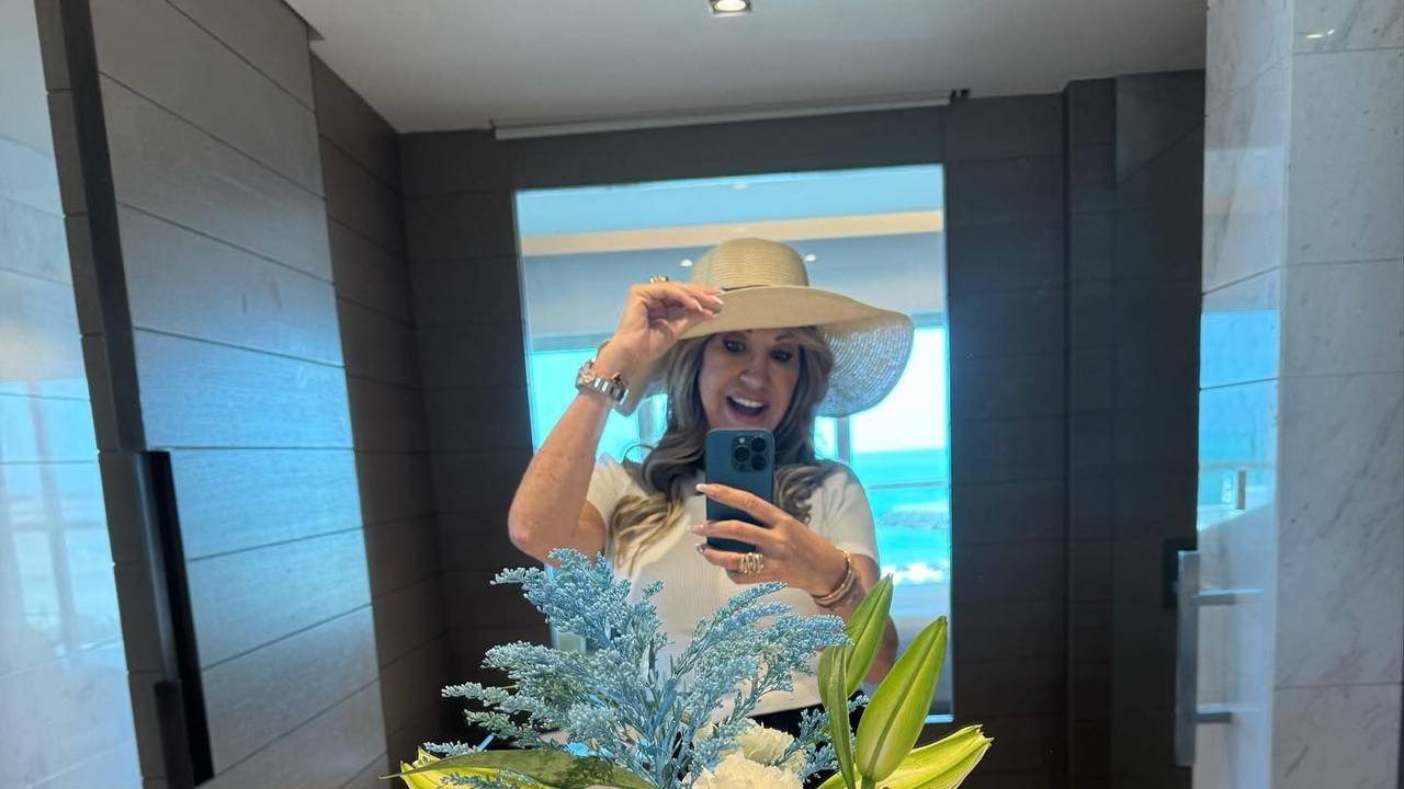 Carmen Geiss steht vor einem Spiegel und macht ein Selfie. Sie trägt einen Hut und lächelt.