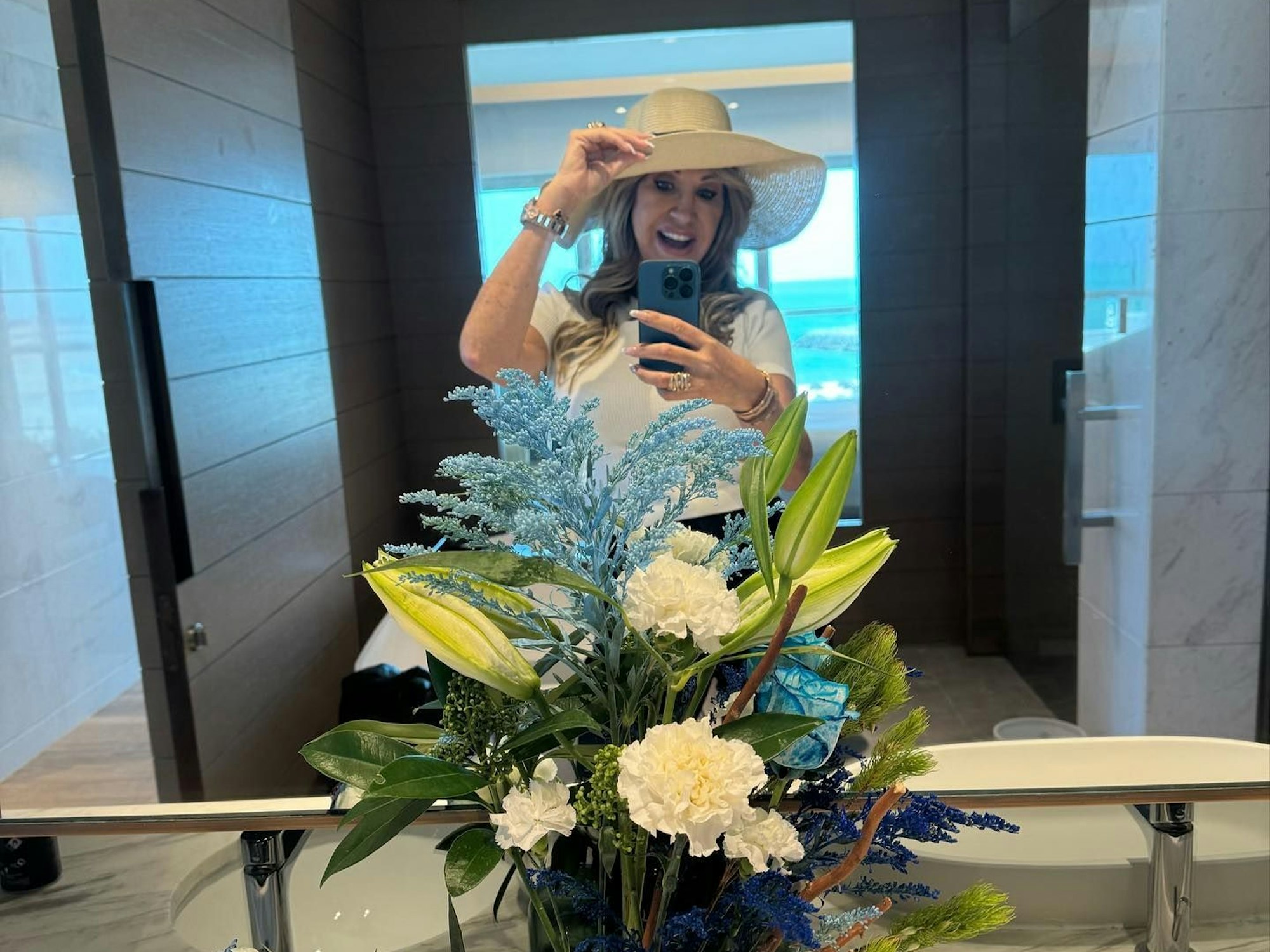 Carmen Geiss steht vor einem Spiegel und macht ein Selfie. Sie trägt einen Hut und lächelt.