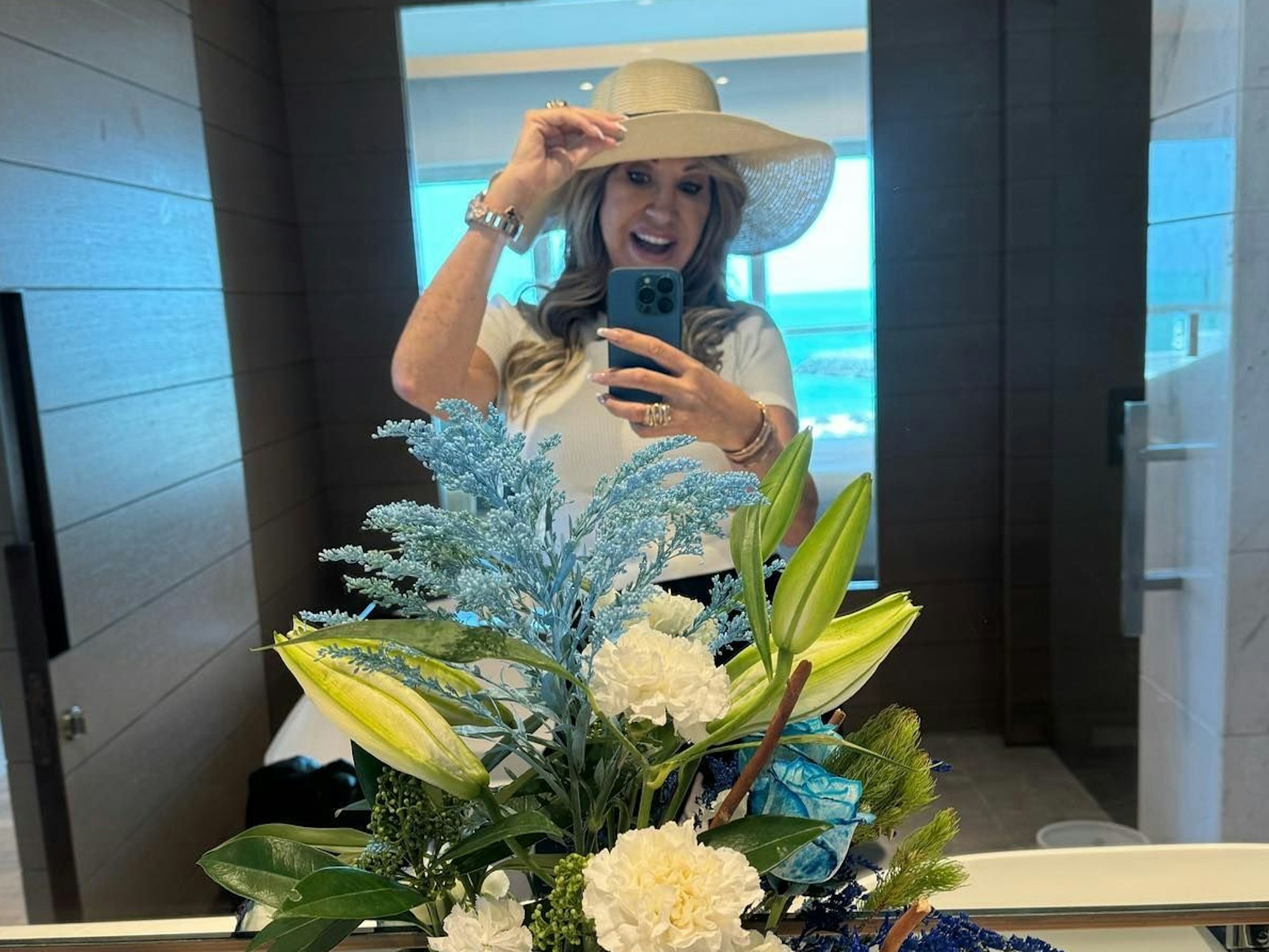 Carmen Geiss steht vor einem Spiegel und macht ein Selfie. Sie trägt einen Hut und lächelt.