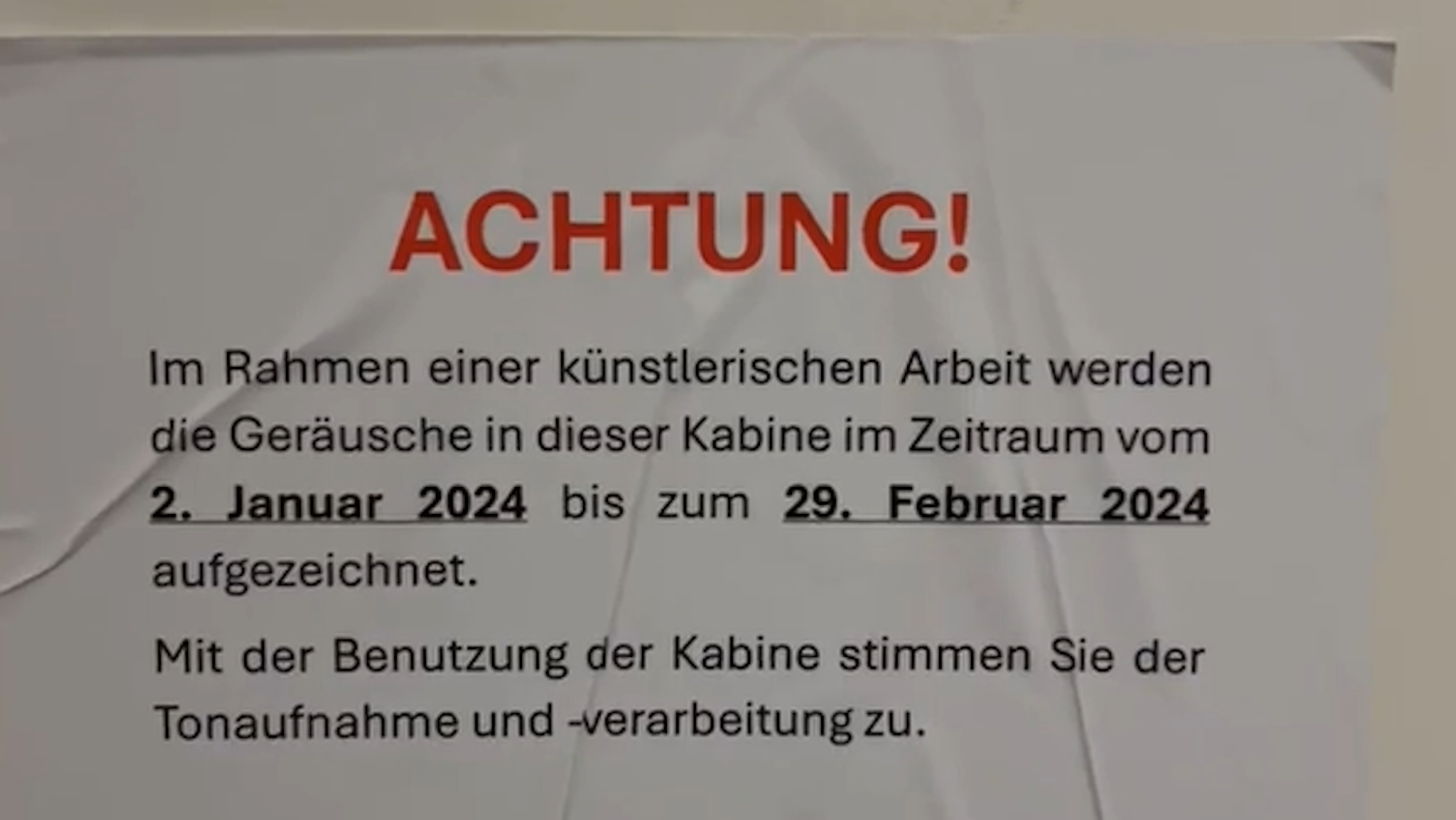 Ein Zettel hängt an einer Wand.