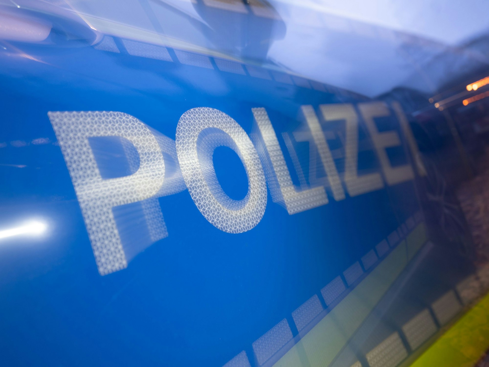 Das Wort Polizei ist im Rahmen eines Fototermins auf der Karosserie eines Polizeifahrzeugs zu sehen (gestellte Szene, Wischeffekt durch Langzeitbelichtung).