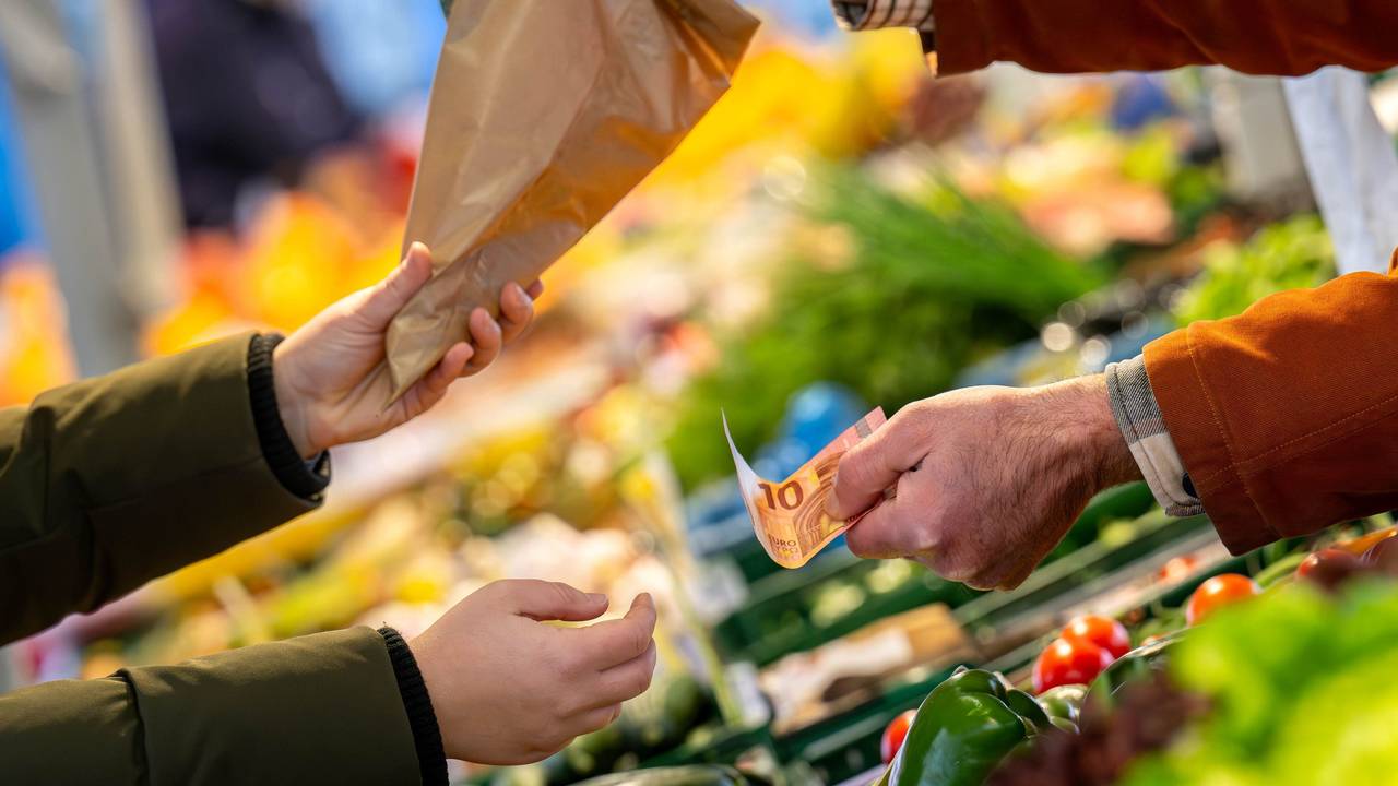 An einem Marktstand wird mit Bargeld eingekauft