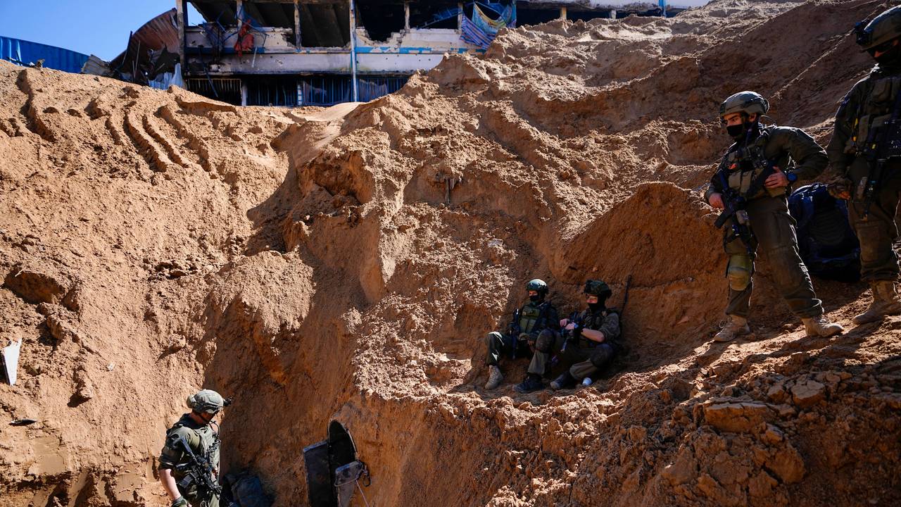 Soldaten bewachen ein kraterähnliches Loch, das zu einem kleinen Tunneleingang führt.