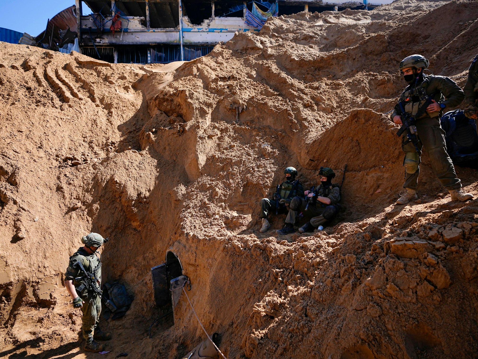 Soldaten bewachen ein kraterähnliches Loch, das zu einem kleinen Tunneleingang führt.