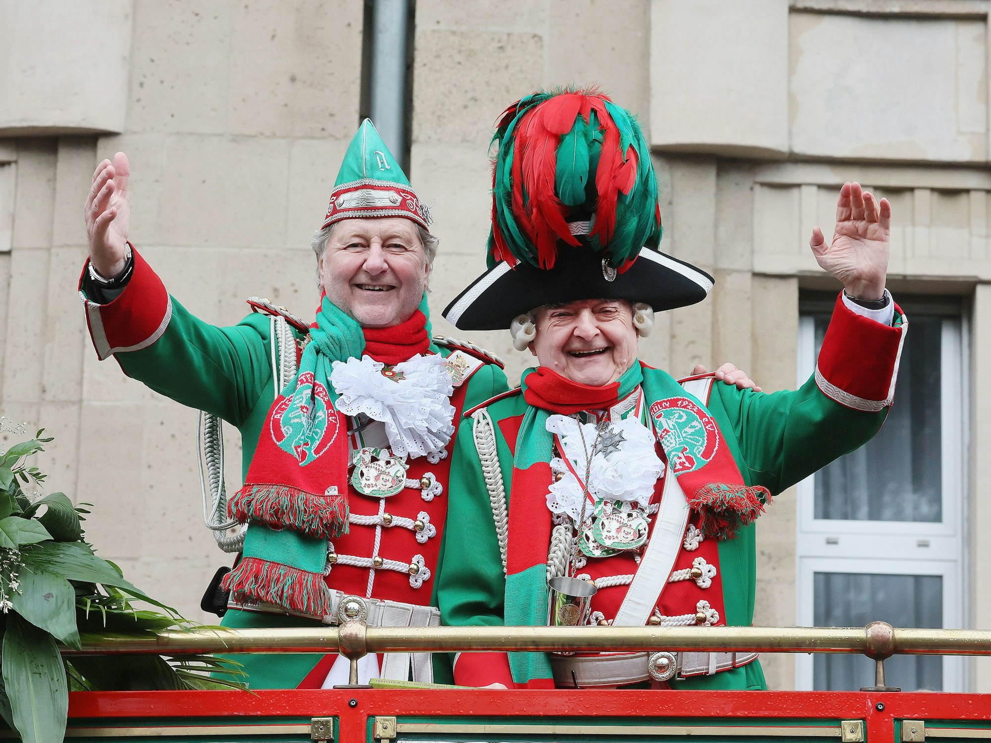 Herbert Reul steht neben einem anderen Mann, beide in Karnevalsuniform und winkend, auf einem Karnevalswagen.