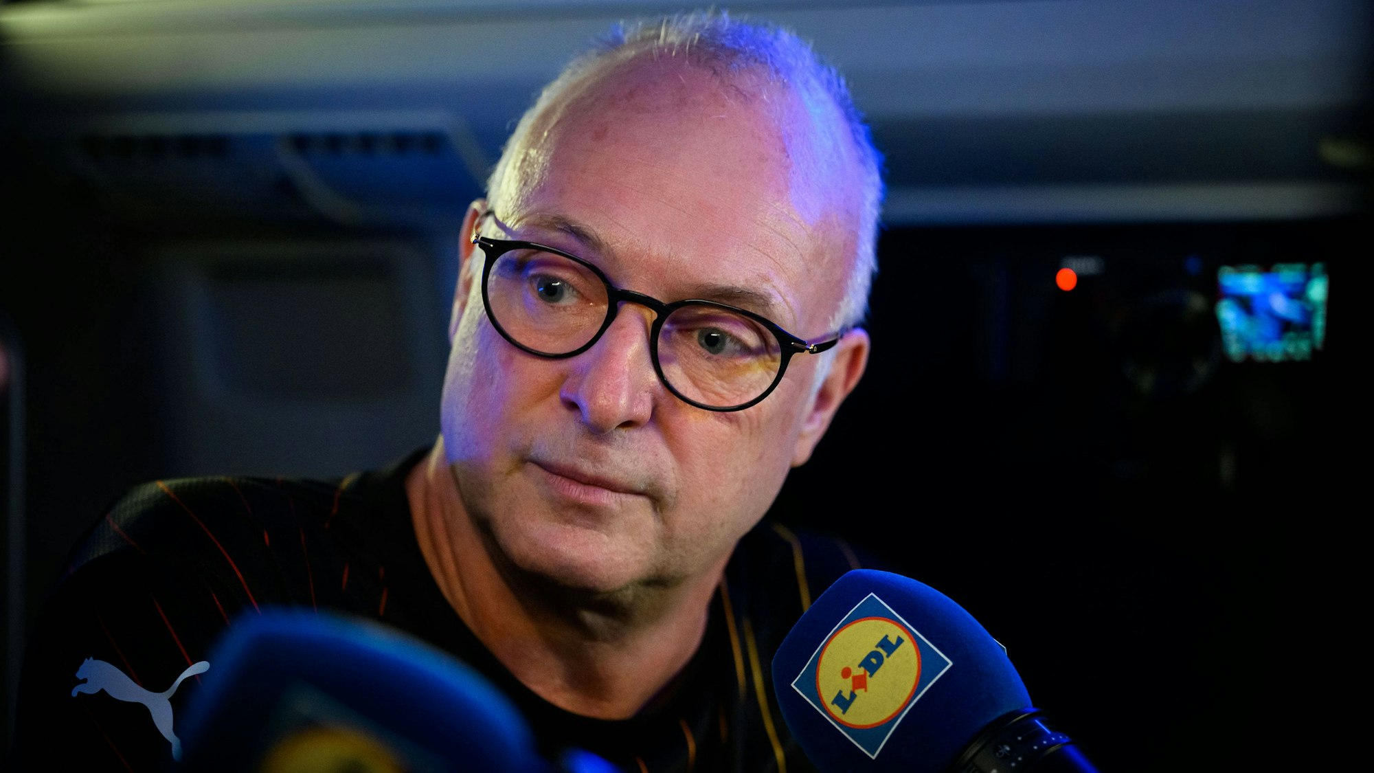 Frank Buschmann sitzt bei einer Aufzeichnung vor einem Mikrofon.