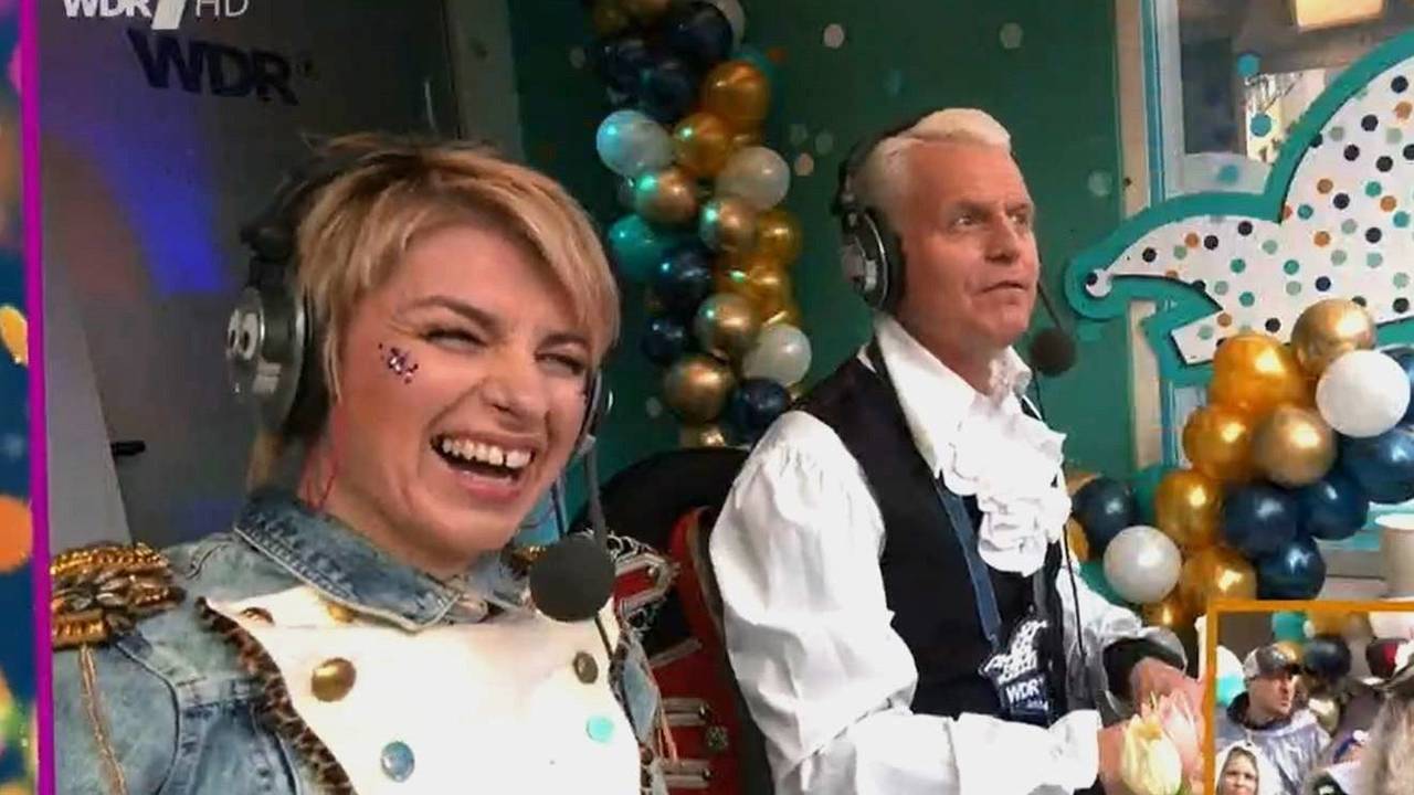 Guido Cantz und Sabine Heinrich sitzen in einer Reporter-Kabine.