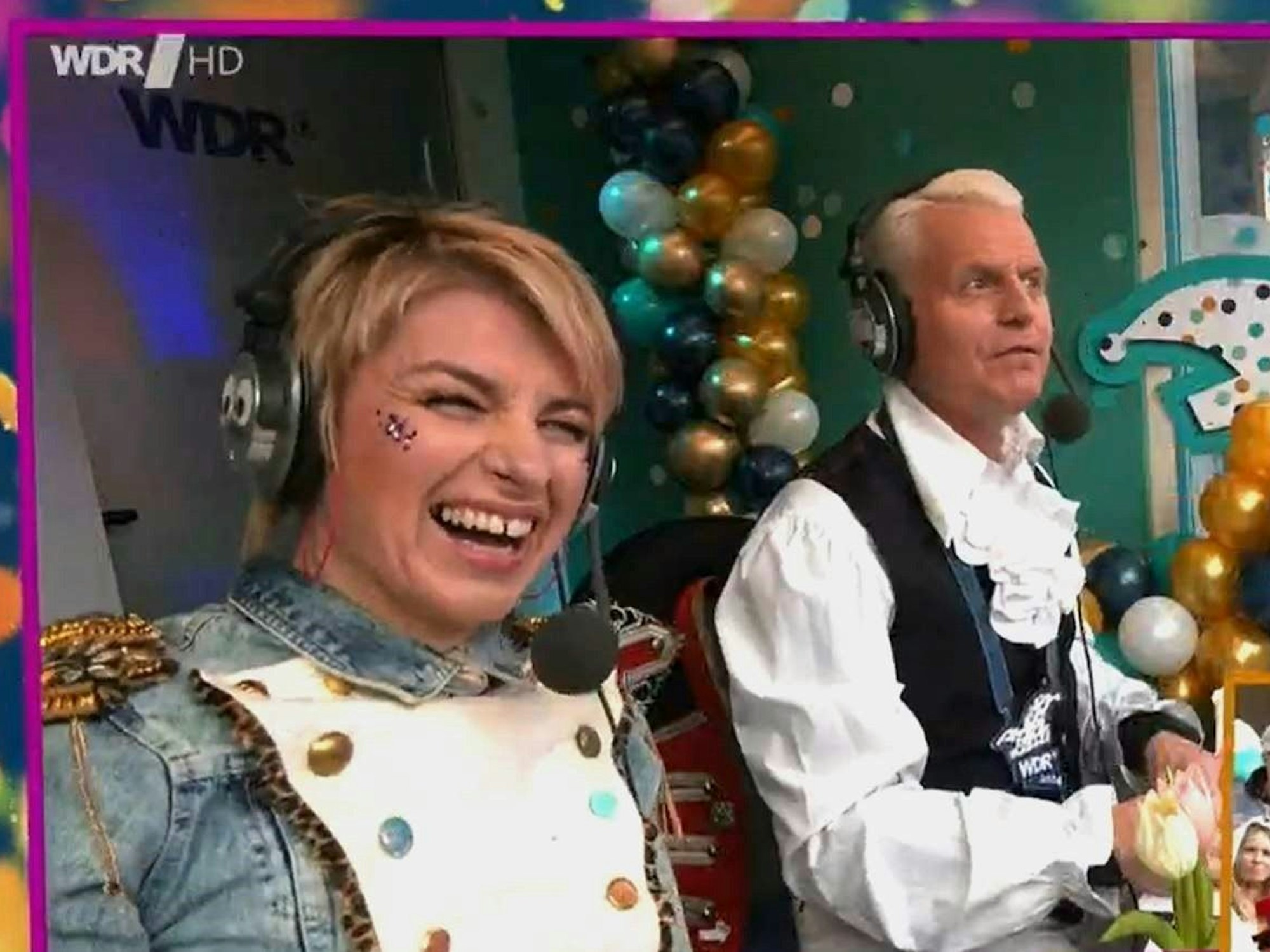 Guido Cantz und Sabine Heinrich sitzen in einer Reporter-Kabine.