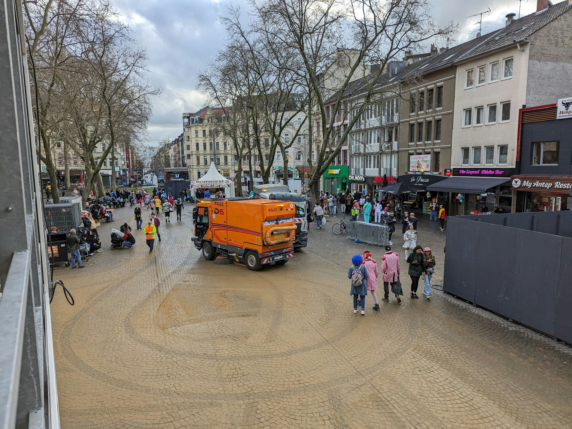 Ein Reinigungswagen fährt über einen Platz.