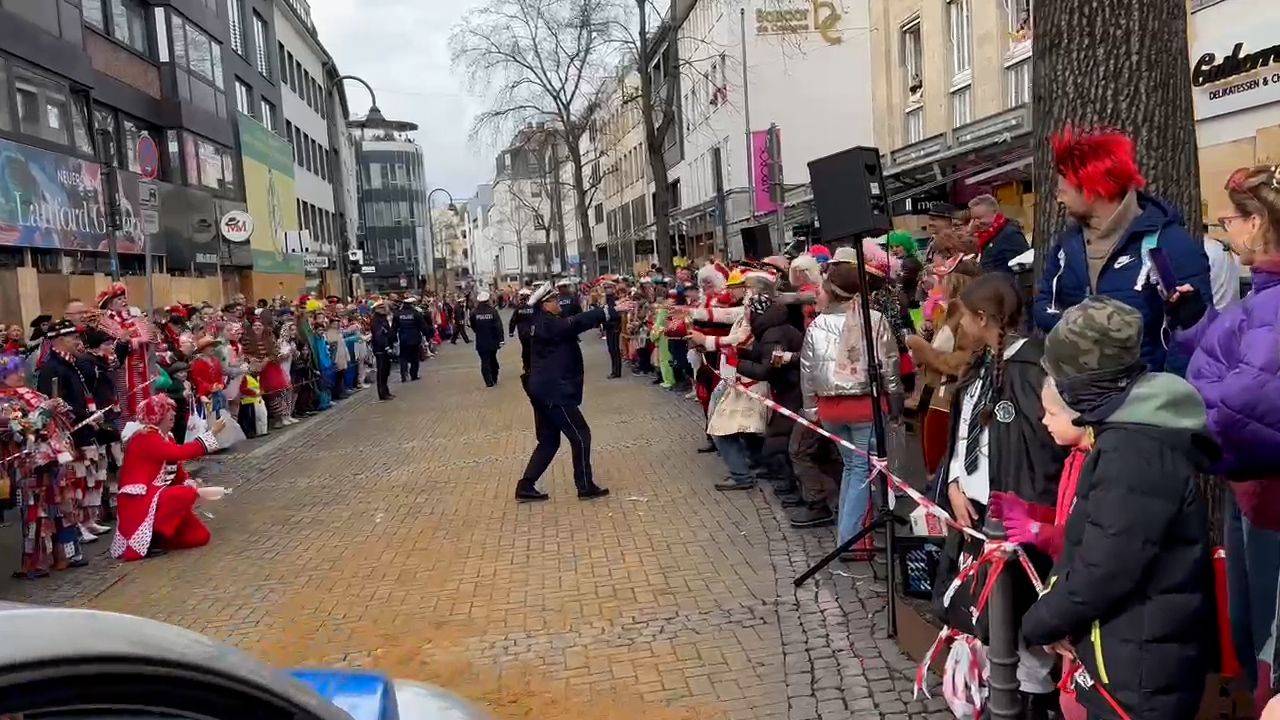 Tanzende Polizistin im Rosenmontagszug in Köln feiert mit den Jecken.