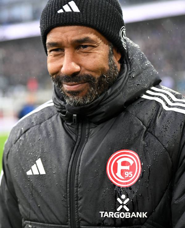 Fortuna Düsseldorfs Cheftrainer Daniel Thioune steht beim Auswärtsspiel beim SC paderborn im Stadion und lächelt.