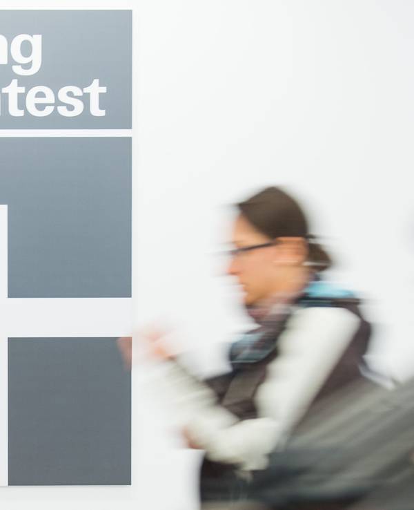 Eine Frau geht an dem Logo der Stiftung Warentest vorbei.