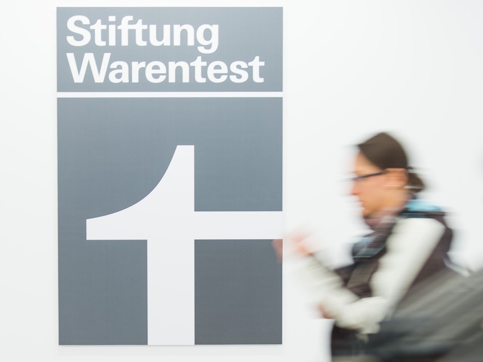 Eine Frau geht an dem Logo der Stiftung Warentest vorbei.