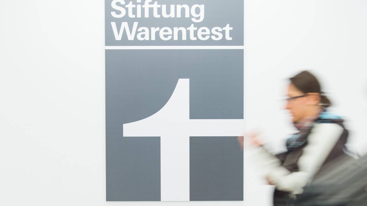 Eine Frau geht an dem Logo der Stiftung Warentest vorbei.