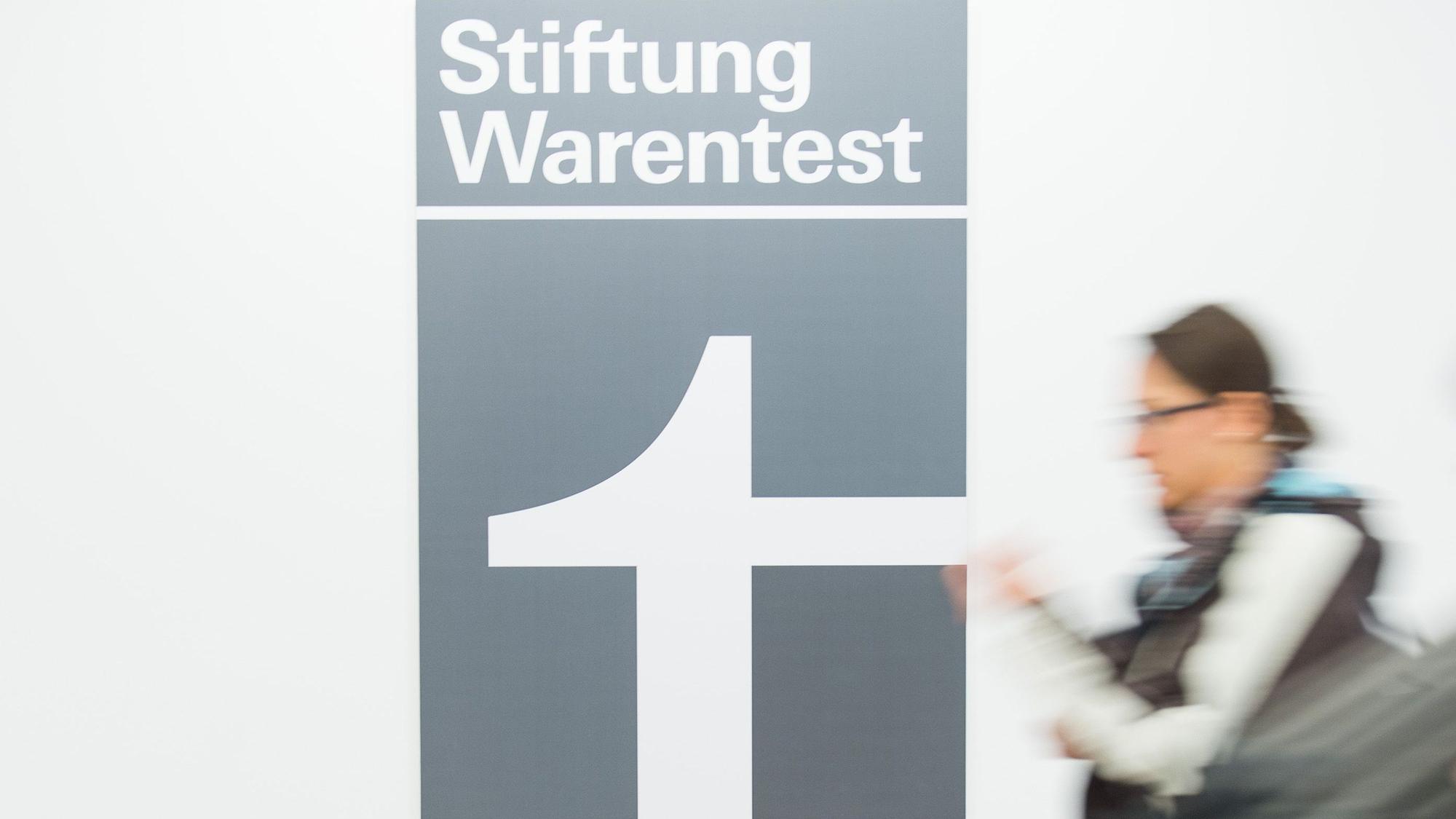 Eine Frau geht an dem Logo der Stiftung Warentest vorbei.