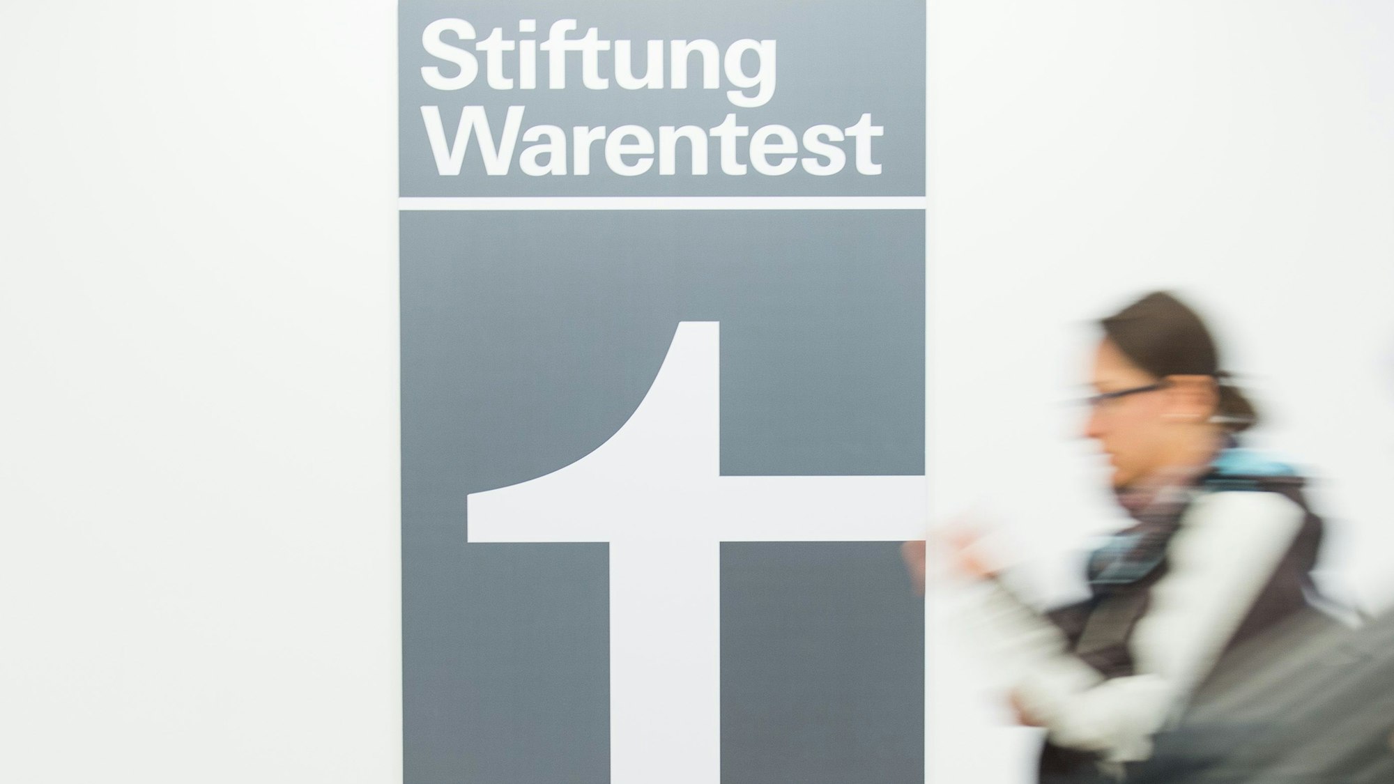 Eine Frau geht an dem Logo der Stiftung Warentest vorbei.