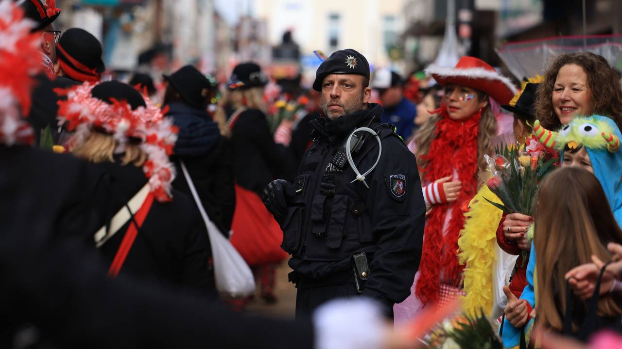 Ein Polizist steht inmitten von Karnevalistinnen und Karnevalisten im Rosenmontagsumzug.