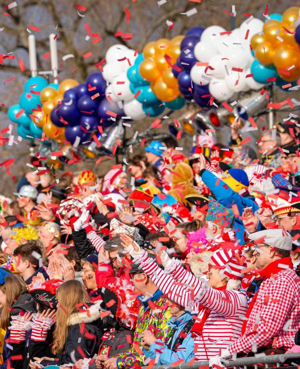 Menschen werfen Konfetti beim Kölner Rosenmontagszug.
