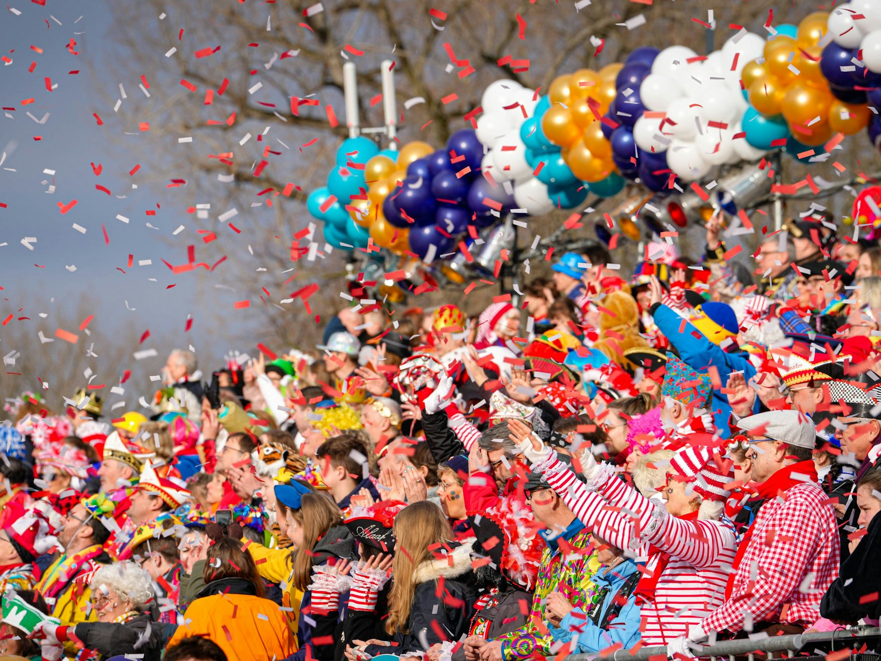 Menschen werfen Konfetti beim Kölner Rosenmontagszug.