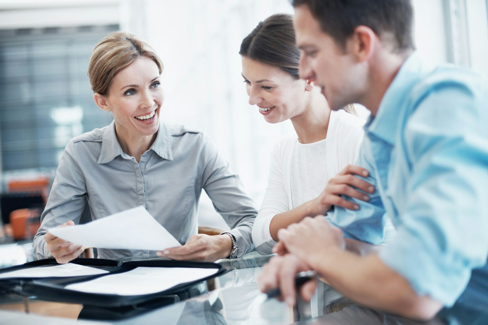Eine Frau erklärt ein Dokument zu einem jungen Paar