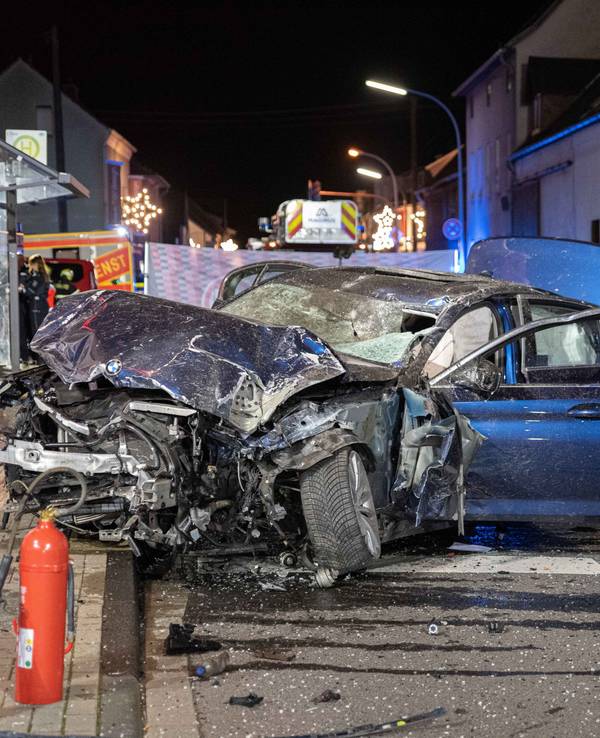 Ein völlig beschädigtes Auto steht nach einem Unfall vor einer Bushaltestelle.