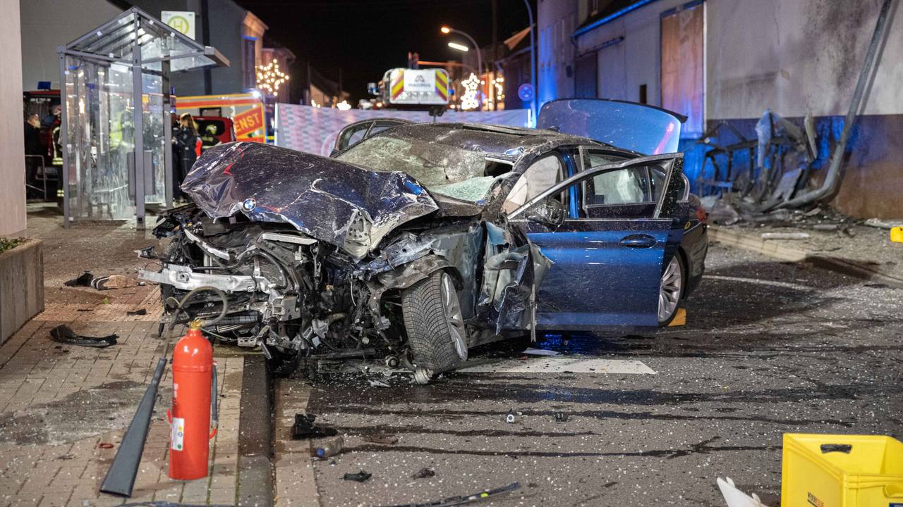 Ein völlig beschädigtes Auto steht nach einem Unfall vor einer Bushaltestelle.