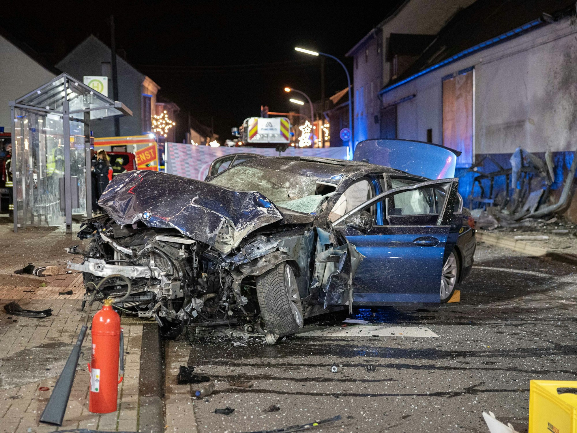 Ein völlig beschädigtes Auto steht nach einem Unfall vor einer Bushaltestelle.