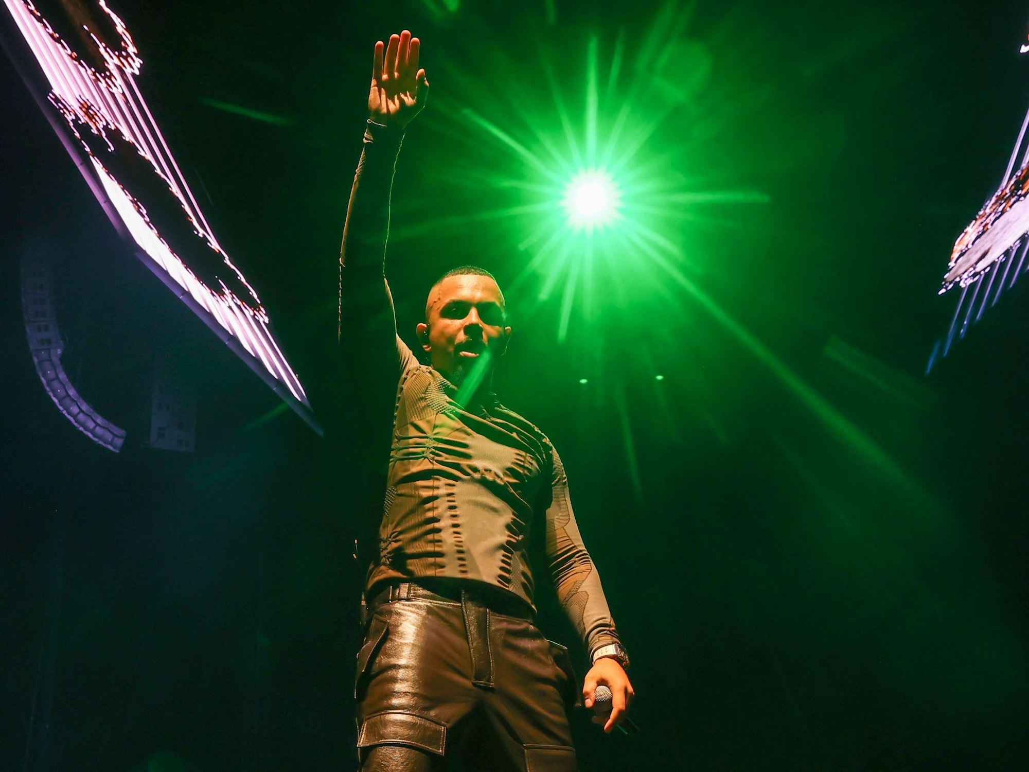 Rapper Luciano steht auf der Bühne und hebt einen Arm hoch.