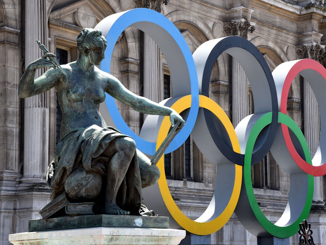 Die Olympischen Ringe vor dem Pariser Rathaus, links daneben eine weibliche Statue