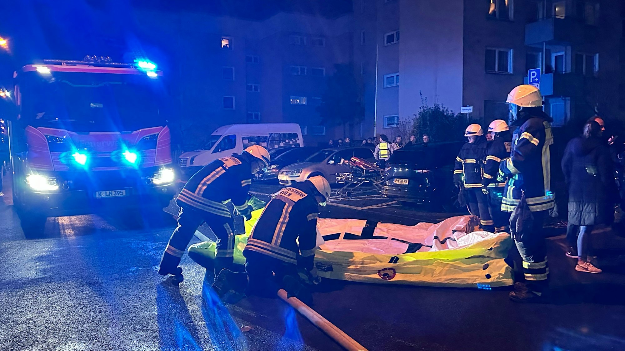 Einsatzkräfte der Kölner Feuerwehr stehen vor einem Haus.