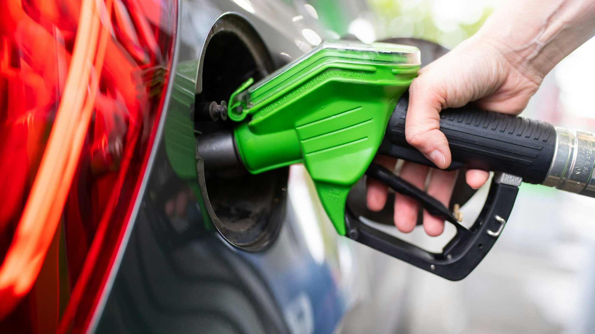 Eine Frau hält an einer Tankstelle an einer Zapfsäule eine Zapfpistole in der Hand und betankt ein Auto. Die Spritpreise sind in den vergangenen Tagen spürbar gestiegen.