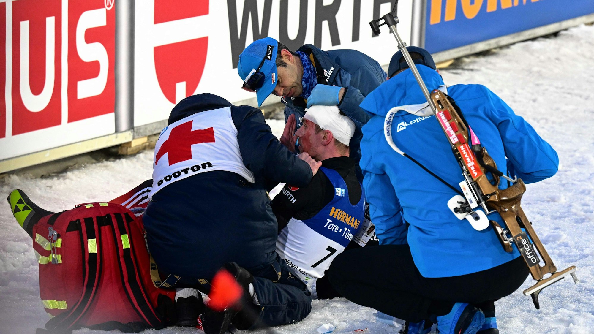 Johannes Kühn wird nach seinem Sturz bei der Biathlon-WM im Ziel ein Kopfverband angelegt.